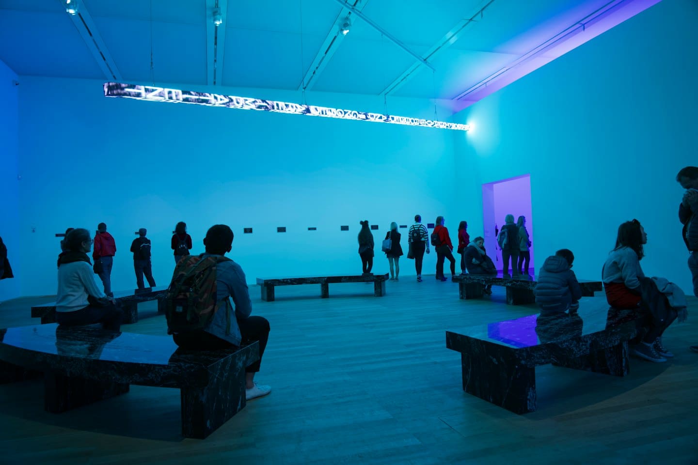 Persone che ammirano un'installazione di arte astratta luminosa in una galleria.