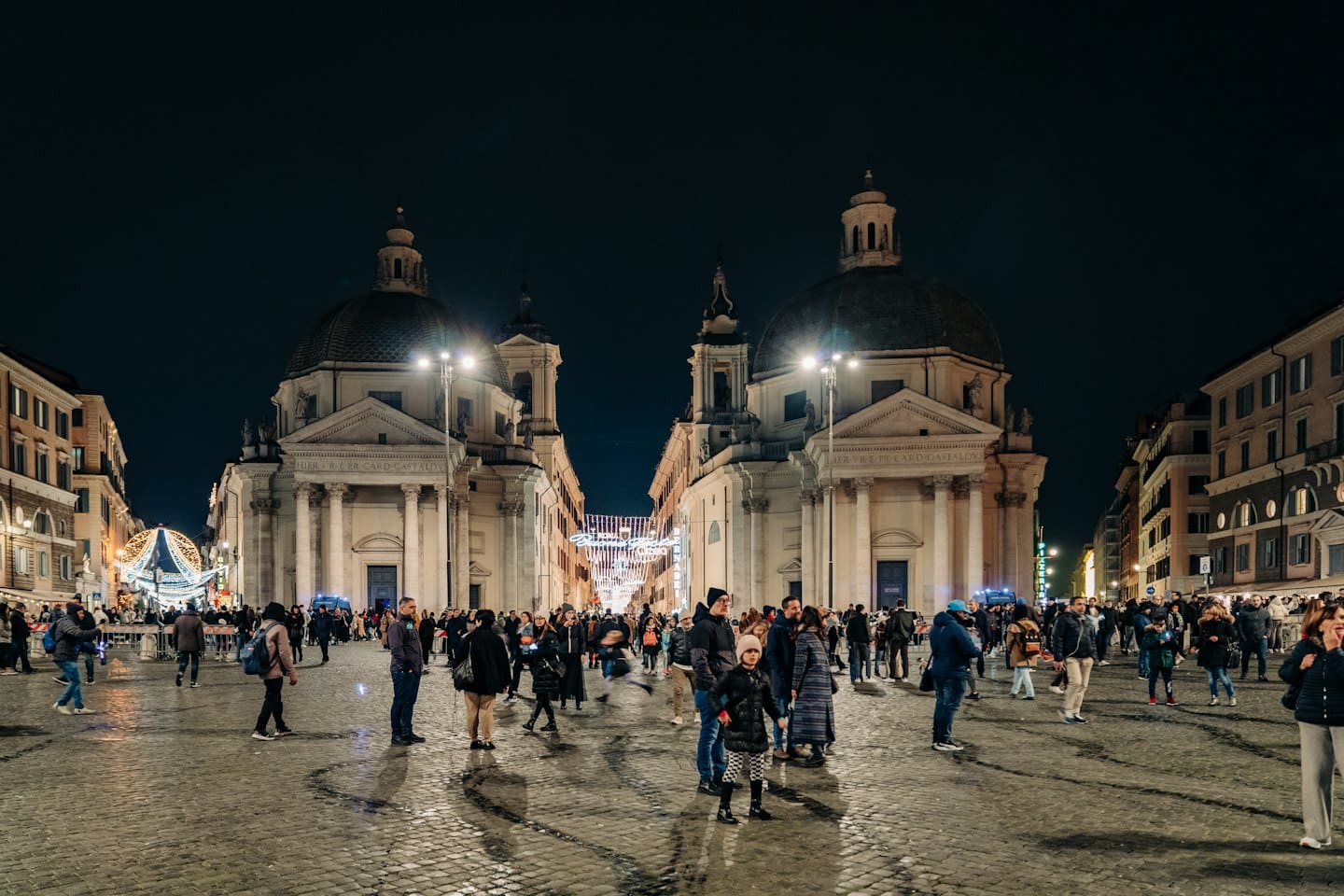 Persone passeggiano in una piazza cittadina animata con edifici storici.