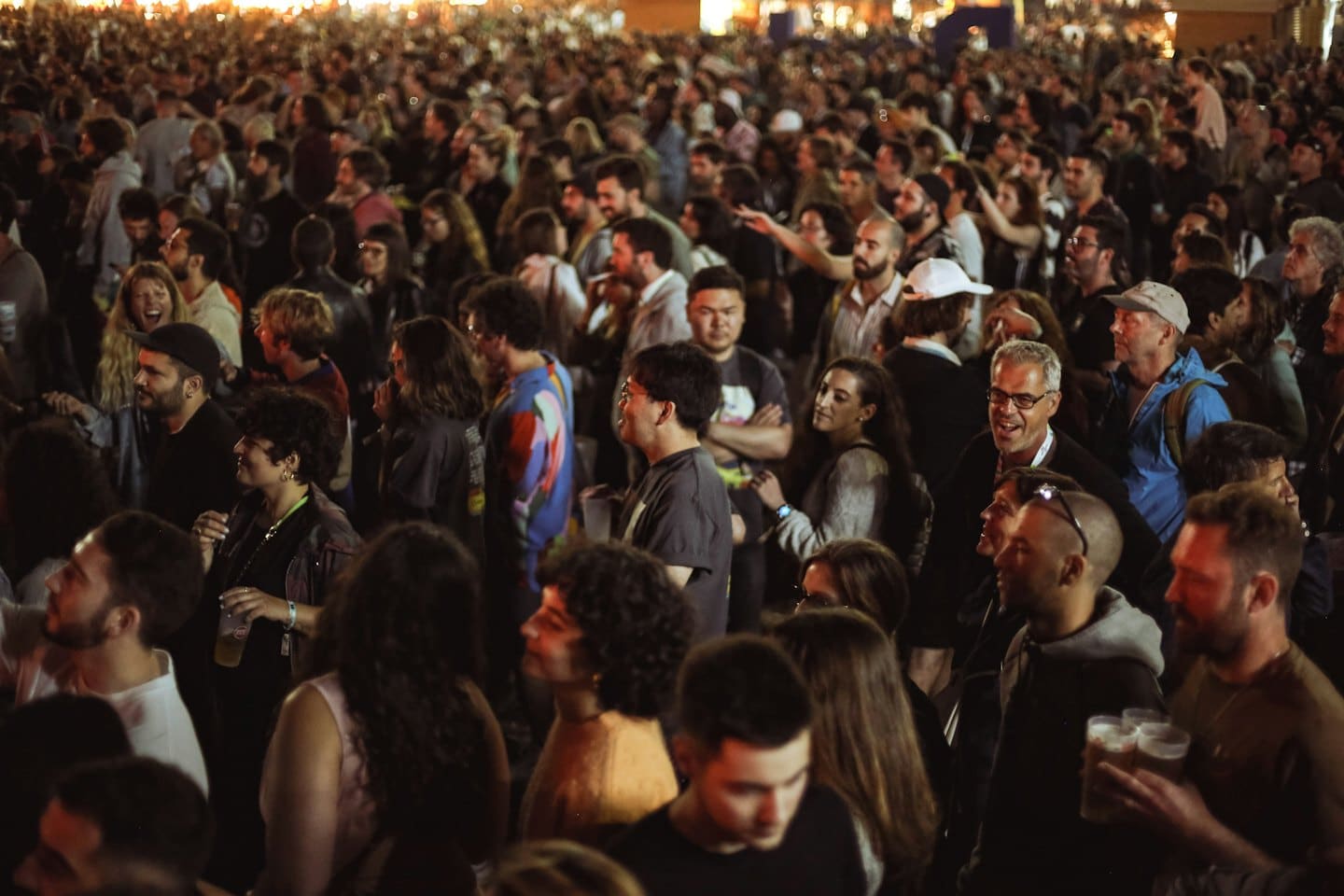Una folla di persone socializza con drink all'aperto di notte.
