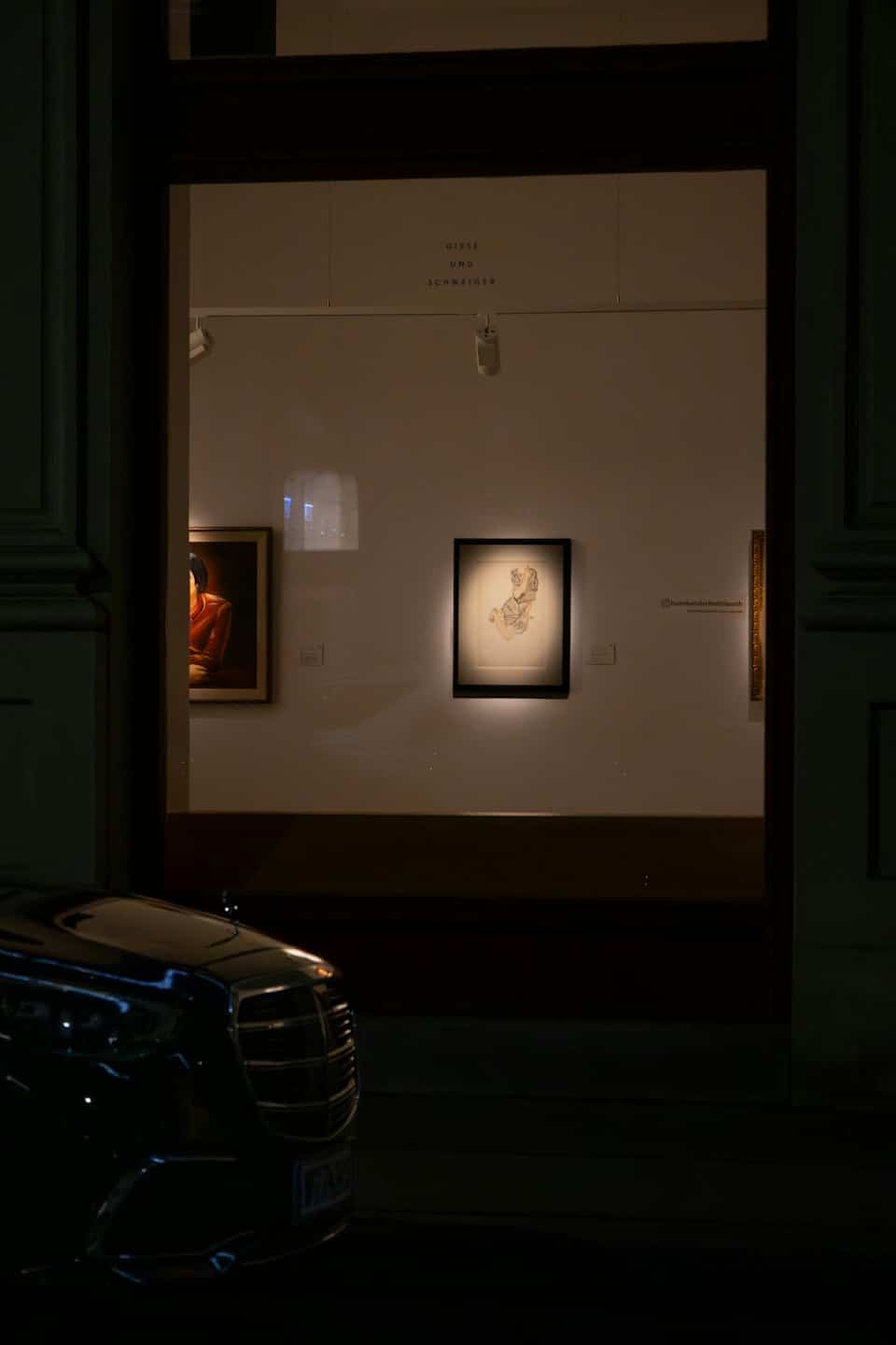 Opera d'arte illuminata esposta nella vetrina di una galleria d'arte contemporanea di notte.