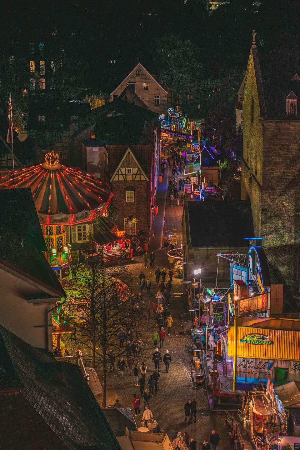 Festa di strada di notte con luci colorate e folla.
