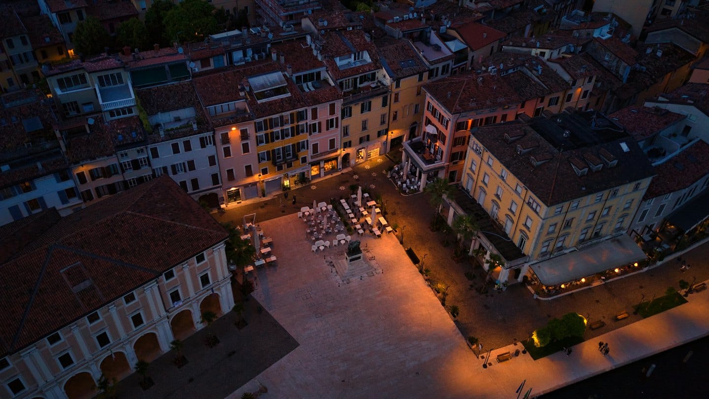 Piazza storica europea al tramonto con tavoli all'aperto.