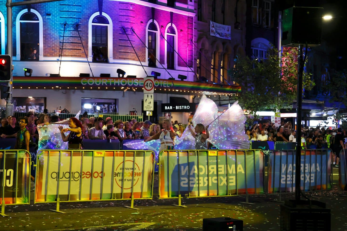 Artisti con ali luminose danzano a una festa di strada all'aperto.